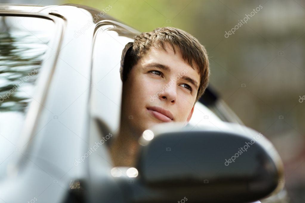 Teen driver in good mood with black car, selective focus on eyes