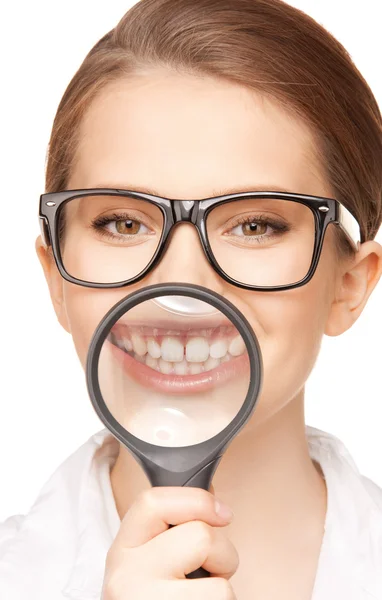 Woman with magnifying glass showing teeth — Stock Photo, Image