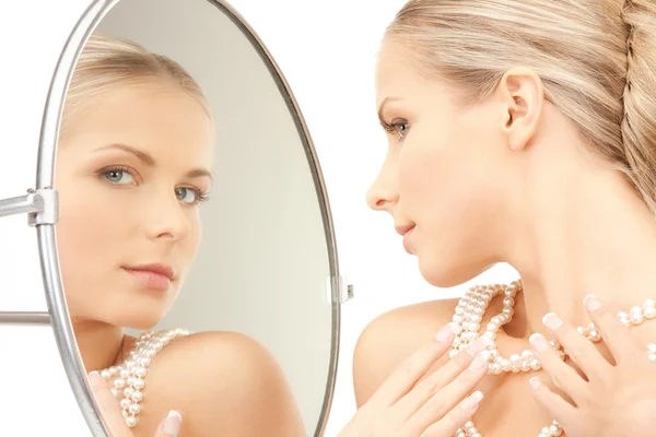 Красивая женщина с жемчужными бусами и зеркалом — стоковое фото