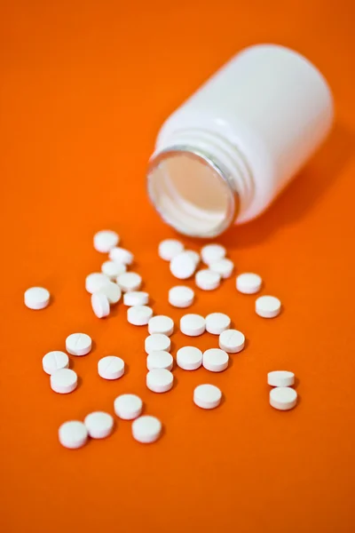 Белая таблетка на оранжевом фоне — стоковое фото