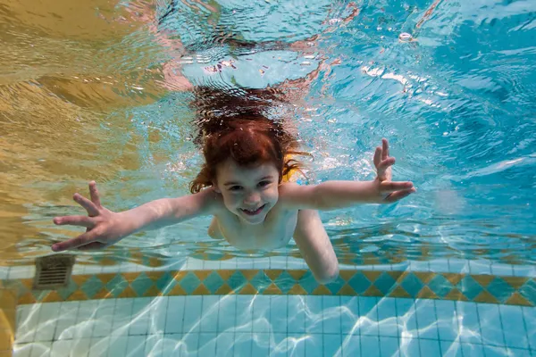 Flicka leenden, simma under vatten i poolen — Stockfoto