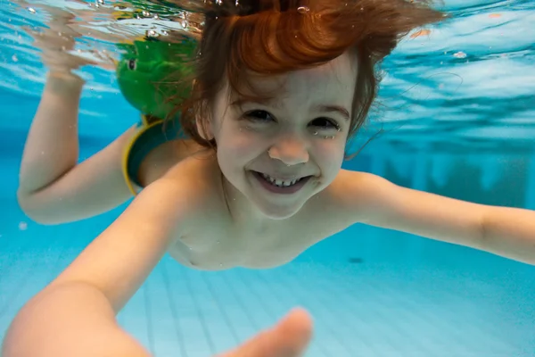 A menina sorri, nadando debaixo d 'água na piscina — Fotografia de Stock