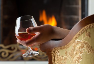 Resting at the burning fireplace fire with a glass of cognac clipart