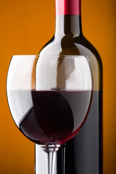Una botella de vino tinto y un primer plano de copa de vino — Foto de Stock