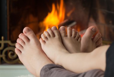 Çocuk ayak şöminede bir açık ateş tarafından ısıtılır