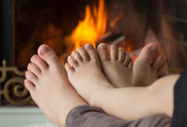 Children's feet are heated by an open fire in the fireplace clipart