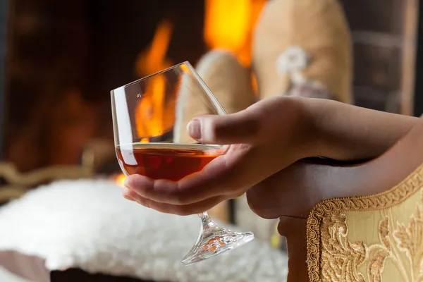 Resting at the burning fireplace fire with a glass of cognac — Stock Photo, Image