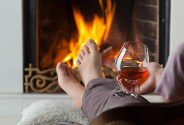 stock image Resting at the burning fireplace fire with a glass of cognac