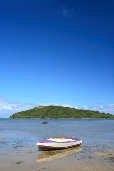 Moored boat, reflected in shallow water at low tide