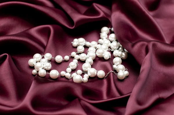 ルビー色のサテンの背景に光沢のある白い真珠 — ストック写真