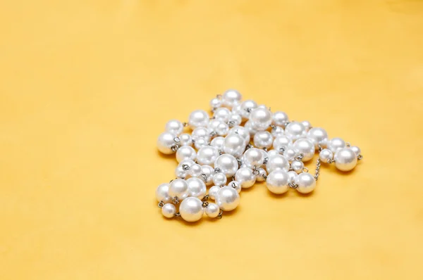 Glänzende Weiße Perlen Auf Gelbem Satinhintergrund — Stockfoto