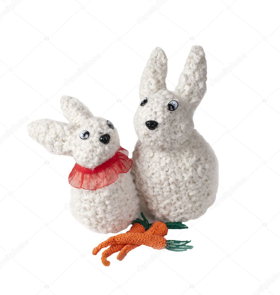 Two isolated toy hares with three carrots