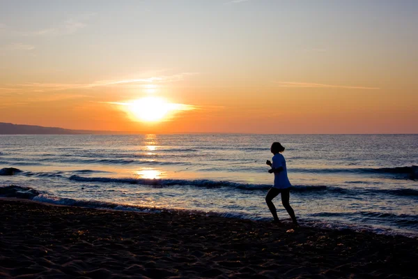 柔らかいパステル調の夕焼け空と海の女性ランナーのシルエット — ストック写真