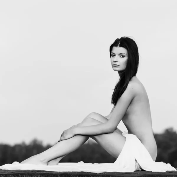 Женщина сидит завернутая в белое полотенце — стоковое фото