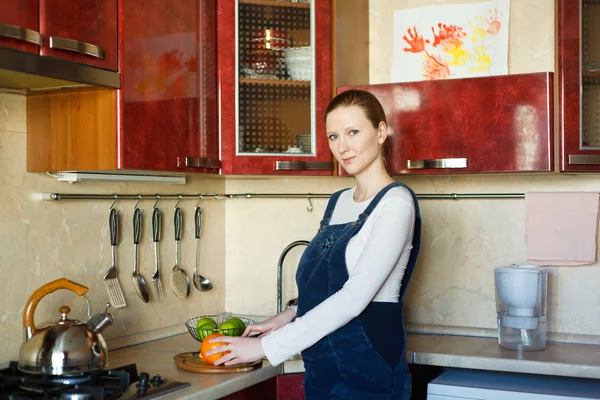 Gravid kvinna skär apelsiner för hennes frukost — Stockfoto