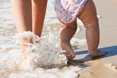 Pretty wonam walking in water with her baby clipart