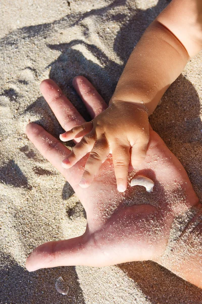 Мать держит своего ребенка за руку на песке — стоковое фото