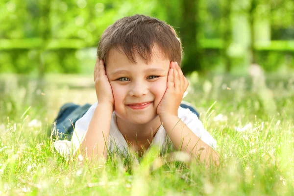 Gelukkig jongetje opleggen op het gras — Stockfoto
