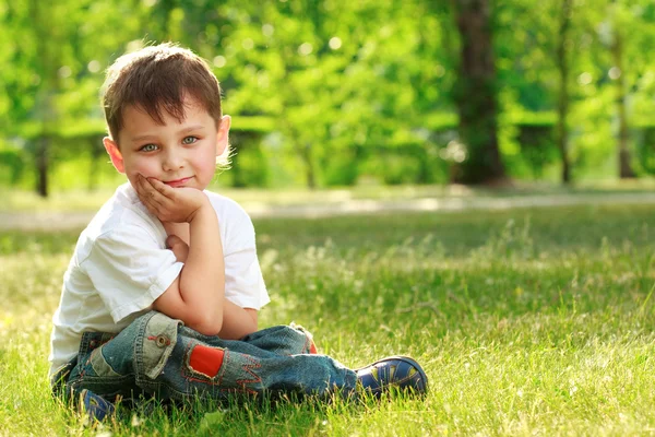 Petit garçon assis sur l'herbe — Photo