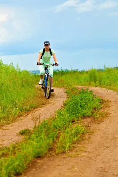 Mujer con bicicleta en el campo verde — Foto de Stock