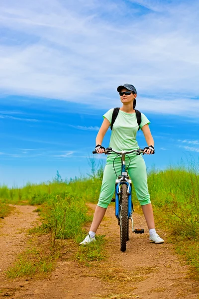 Woman with bike on green field — Stock Photo, Image