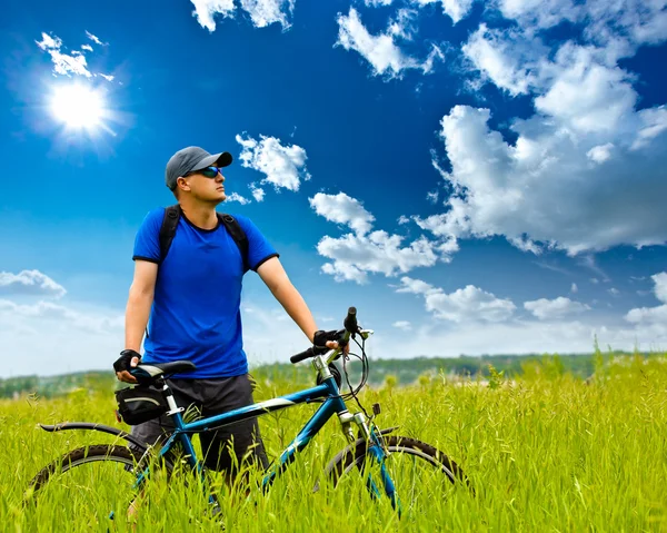 Man with bike on green field — Stock Photo, Image