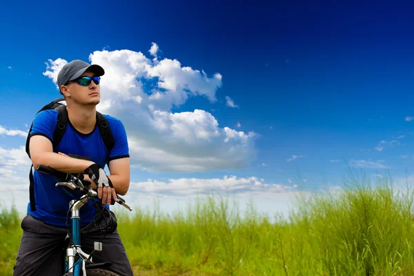 Man with bike on green field — Stock Photo, Image