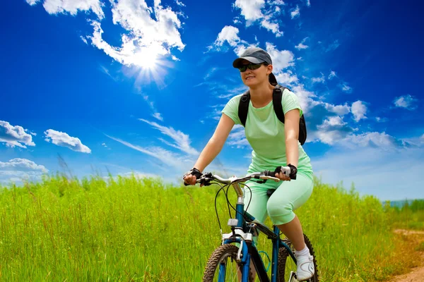 Woman with bike on green field — Stock Photo, Image