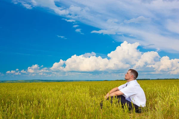 Человек сидит на поле — стоковое фото
