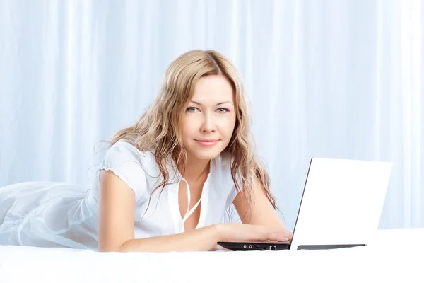 Woman lying on bed with laptop — Stock Photo, Image