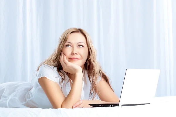 Woman lying on bed with laptop — Stock Photo, Image