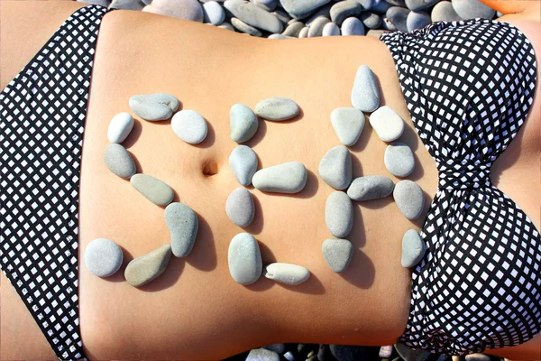 The word "sea" is stated by stones on a abdomen of the girl — Stock Photo, Image