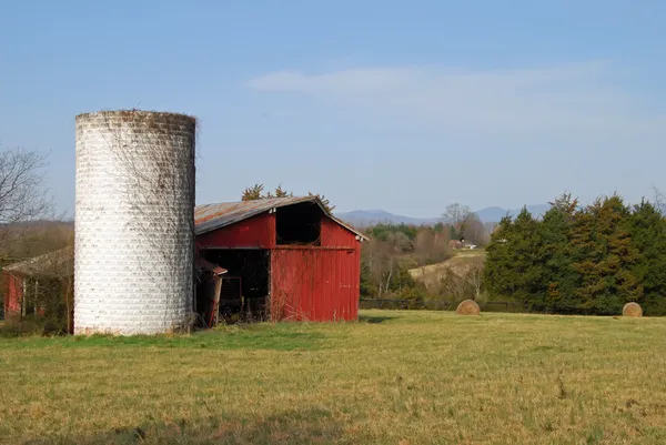Červená stodola a staré bílé silo — Stock fotografie