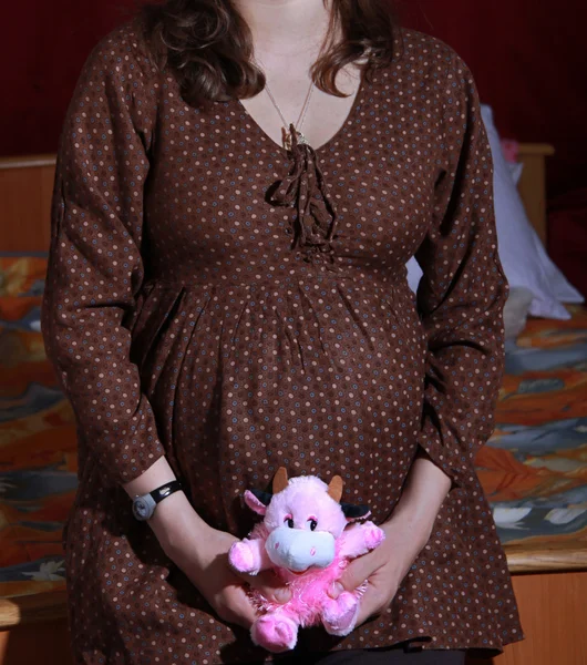 Kobieta w ciąży uśmiechający się zabawka gospodarstwa — Zdjęcie stockowe