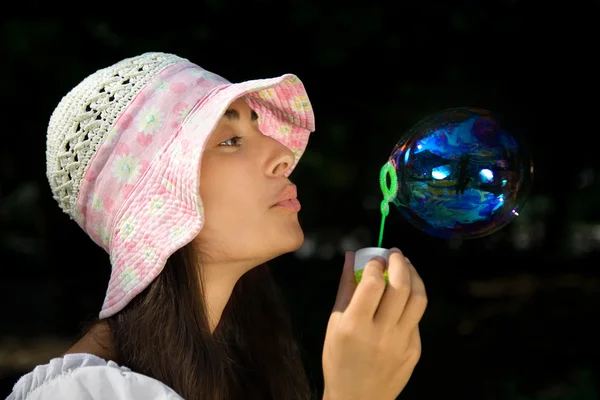Mladá dívka v kapotě vyfukuje bubliny — Stock fotografie