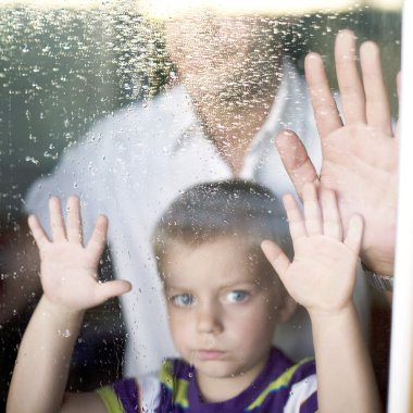 Little boy with his father near window sad,shallow DOF?focus on the hand and the rain drop clipart