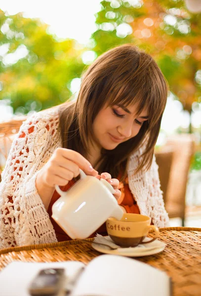 Młoda kobieta pije herbatę w kawiarni na świeżym powietrzu — Zdjęcie stockowe