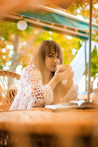 Ung kvinde drikker te i en cafe udendørs - Stock-foto