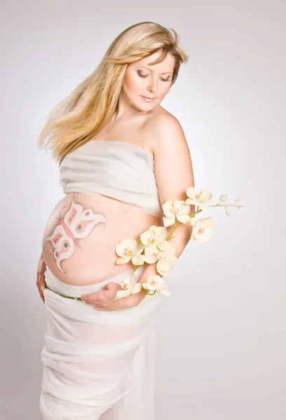 Těhotná mladá žena v látce s orchidejí — Stock fotografie