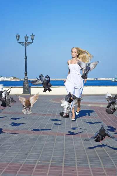 Kvinna mata fåglarna i parken nära havet — Stockfoto