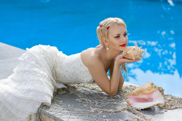Beautiful bride posing near pool with sea shells — Stock Photo, Image