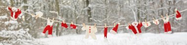 Red santa claus clothes drying in the open air hanging on clothes line affixed with wooden pegs clipart