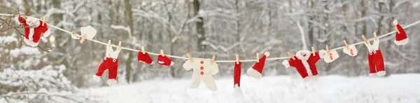 stock image Red santa claus clothes drying in the open air hanging on clothes line affixed with wooden pegs