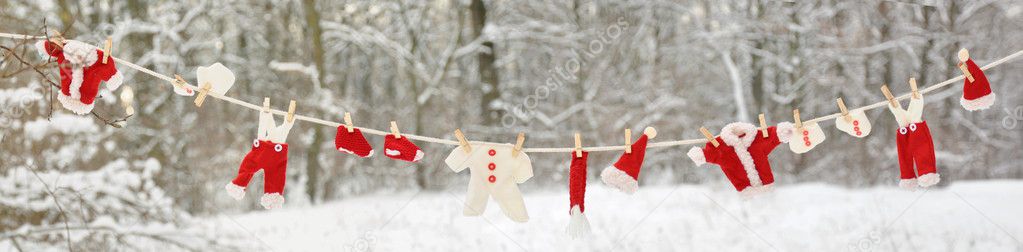 Red santa claus clothes drying in the open air hanging on clothes line affixed with wooden pegs