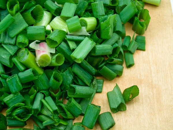Zelené cibule se rozřežou na kuchyňské desce — Stock fotografie