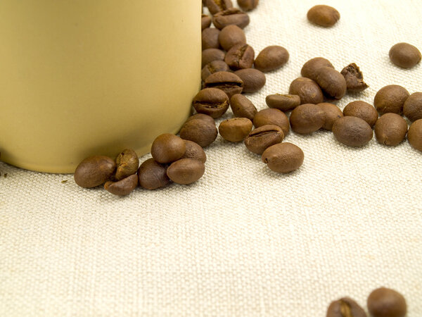Coffee grains near a cup