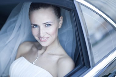 Attractive caucasian bride sitting in car and smile to the camera clipart