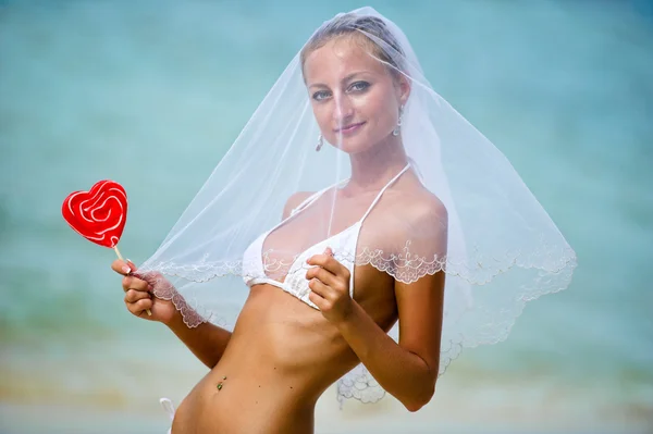 Hermosa chica sosteniendo una piruleta en la playa — Foto de Stock