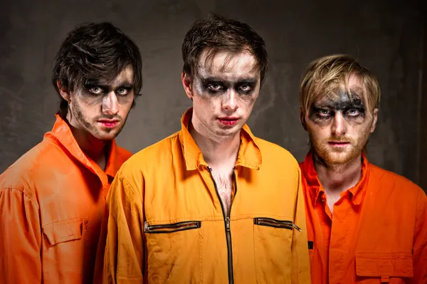 Three criminals in orange uniforms indoors — Stock Photo, Image