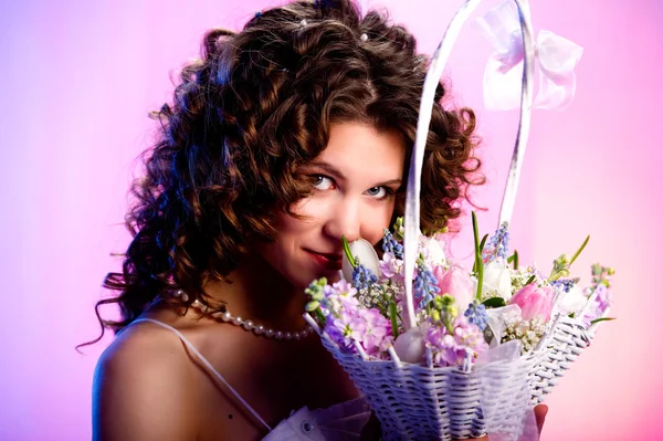 Attractive brunette with a basket of flowers — Stock Photo, Image